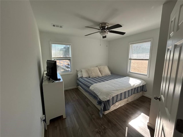 bedroom with dark wood-type flooring, visible vents, baseboards, and multiple windows