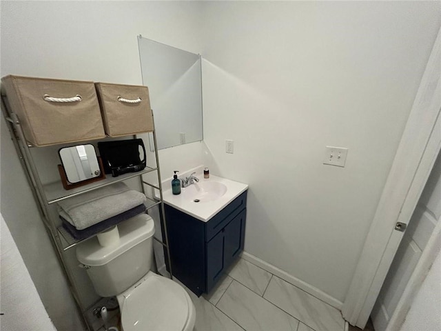 bathroom with toilet, marble finish floor, baseboards, and vanity