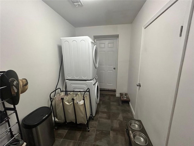 laundry area featuring laundry area, baseboards, visible vents, and stacked washer / drying machine