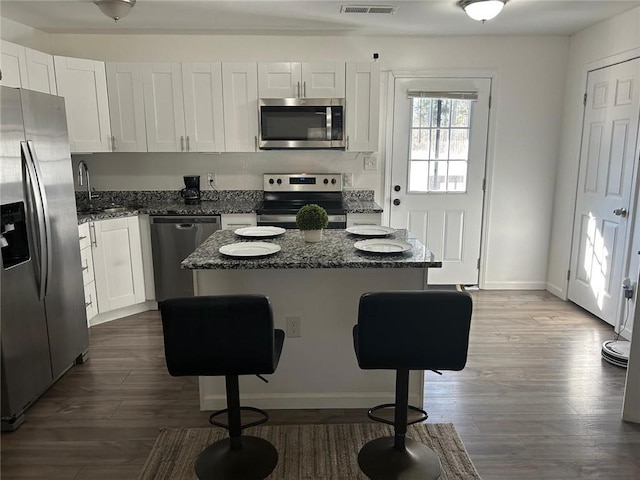 kitchen featuring appliances with stainless steel finishes, a center island, dark wood-style flooring, and white cabinetry