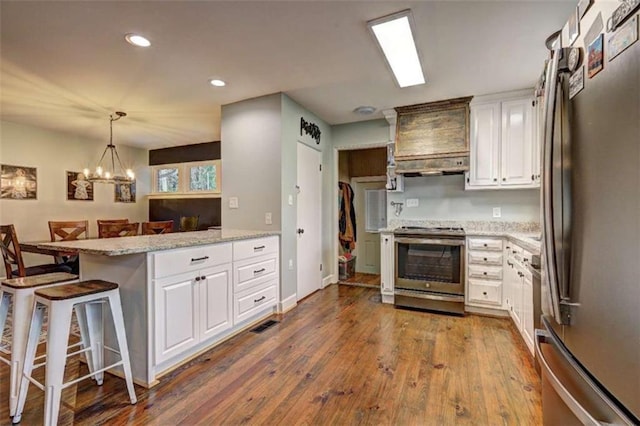 kitchen with white cabinetry, a kitchen breakfast bar, kitchen peninsula, stainless steel appliances, and hardwood / wood-style floors