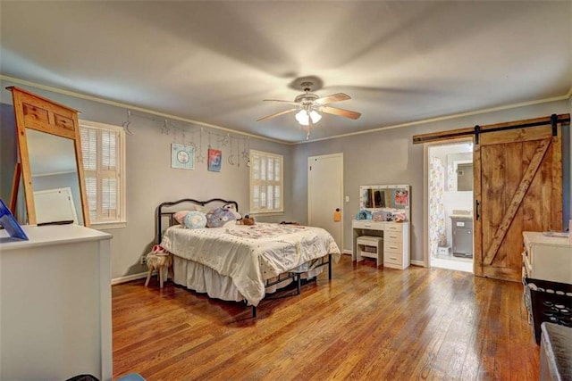 bedroom featuring hardwood / wood-style floors, ornamental molding, and a barn door