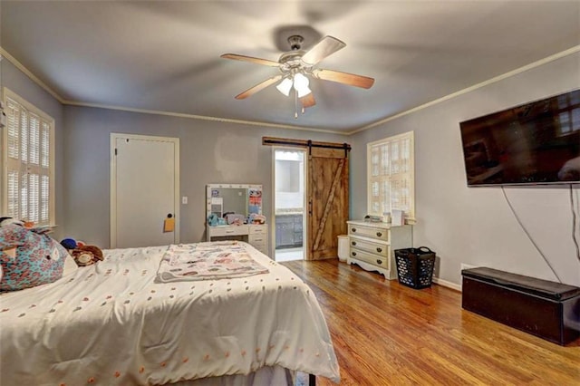 bedroom with ceiling fan, ornamental molding, a barn door, and light hardwood / wood-style flooring