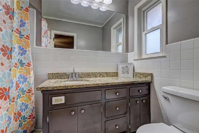 bathroom with vanity, toilet, a shower with shower curtain, and tile walls