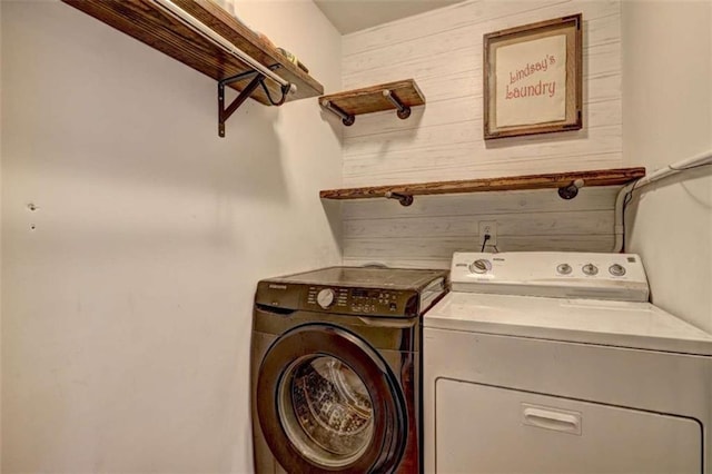 laundry room with washer and dryer and wood walls