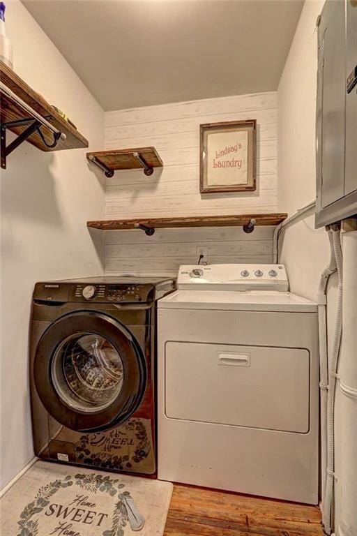 clothes washing area with wooden walls, electric panel, and independent washer and dryer