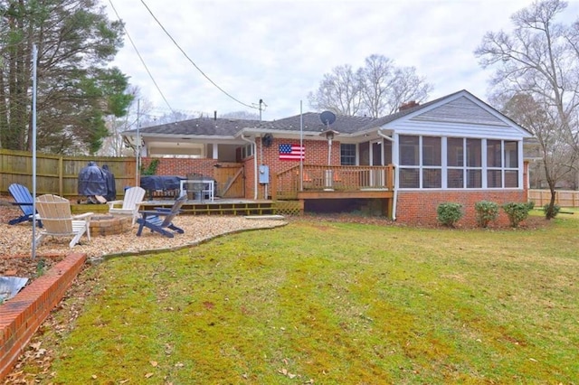 back of house with a wooden deck, a yard, a sunroom, and an outdoor fire pit