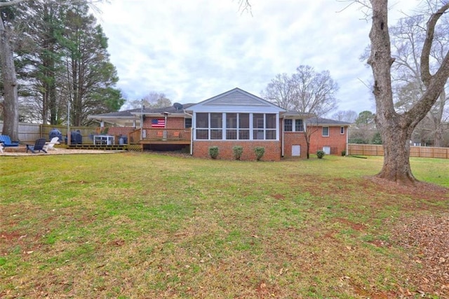 back of house with a wooden deck, a sunroom, and a lawn