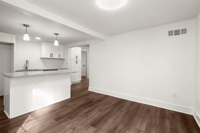 kitchen with white cabinets, dark hardwood / wood-style flooring, decorative light fixtures, and light stone countertops