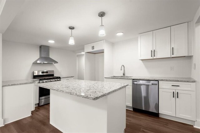 kitchen with white cabinets, appliances with stainless steel finishes, and wall chimney range hood