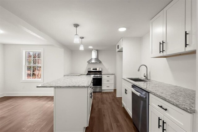 kitchen featuring light stone countertops, appliances with stainless steel finishes, wall chimney exhaust hood, sink, and white cabinetry