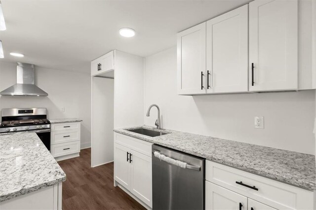 kitchen with white cabinets, sink, wall chimney exhaust hood, dark hardwood / wood-style floors, and appliances with stainless steel finishes