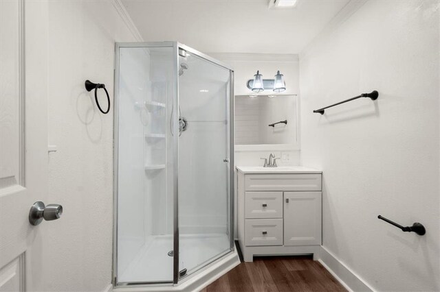 bathroom featuring hardwood / wood-style floors, vanity, ornamental molding, and walk in shower