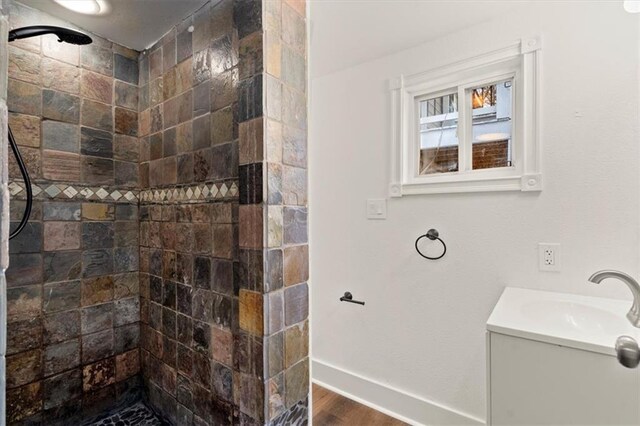 bathroom featuring hardwood / wood-style floors, vanity, and tiled shower