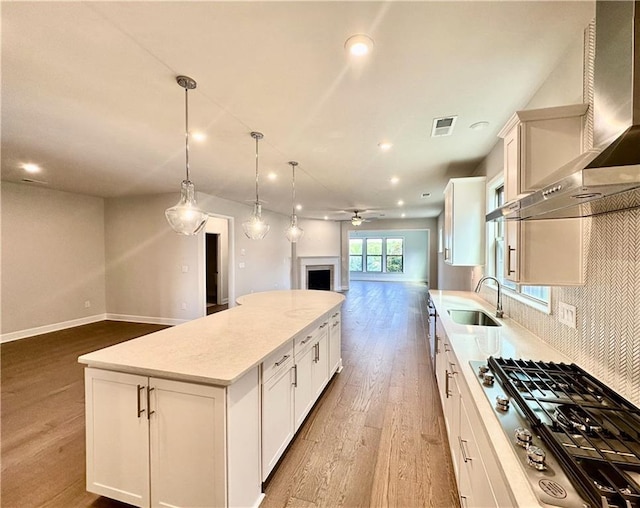 2808 Turnwater St, Hoschton, GA 30548 - kitchen featuring open floor plan, stainless steel gas stovetop, wall chimney range hood, a center island, and wood finished floors