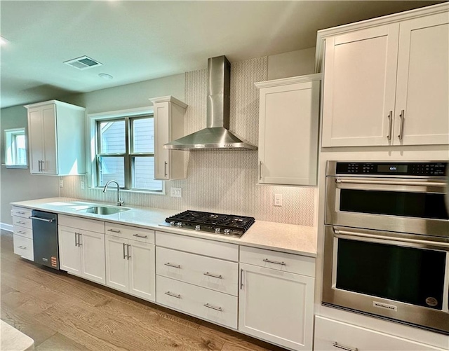 2808 Turnwater St, Hoschton, GA 30548 - kitchen featuring stainless steel appliances, wall chimney range hood, light countertops, light wood-style floors, and white cabinets