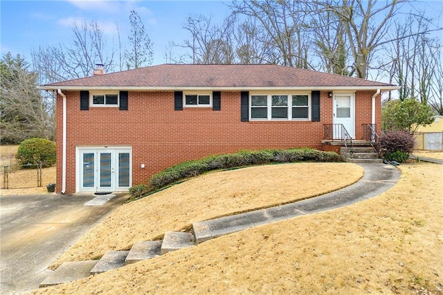 ranch-style home with french doors, brick siding, a chimney, and fence