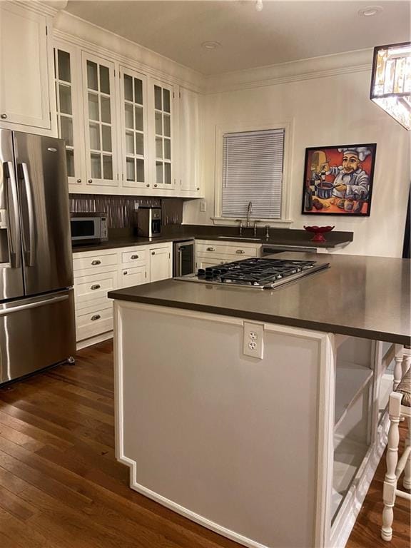 kitchen featuring appliances with stainless steel finishes, white cabinetry, dark wood-type flooring, and tasteful backsplash