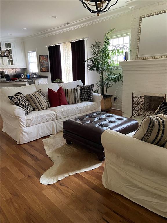 living room with a brick fireplace, ornamental molding, and hardwood / wood-style flooring