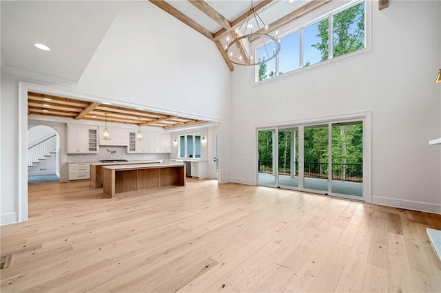 615 Claxton Ln, Milton, GA 30004 - unfurnished living room featuring high vaulted ceiling, beam ceiling, a chandelier, light wood-type flooring, and arched walkways
