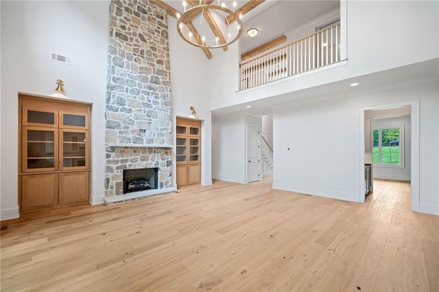 615 Claxton Ln, Milton, GA 30004 - unfurnished living room featuring a towering ceiling, a chandelier, light wood-type flooring, stairs, and a stone fireplace