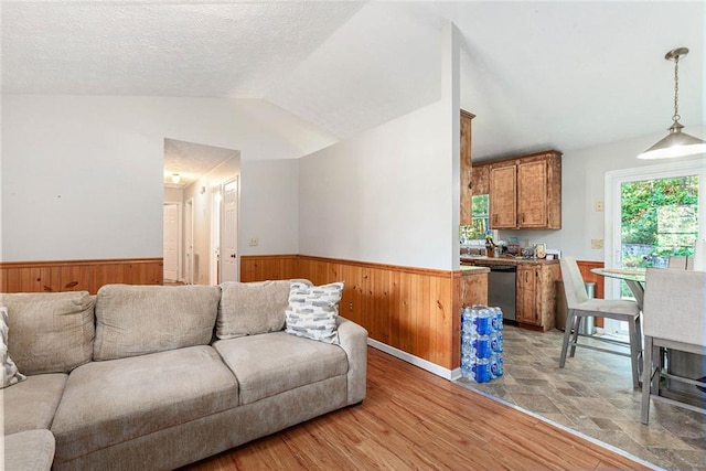 living room featuring a textured ceiling, light wood-type flooring, and vaulted ceiling