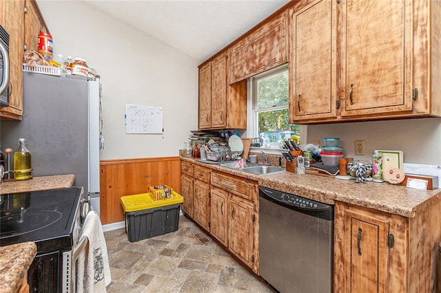 kitchen with range, sink, wooden walls, and stainless steel dishwasher