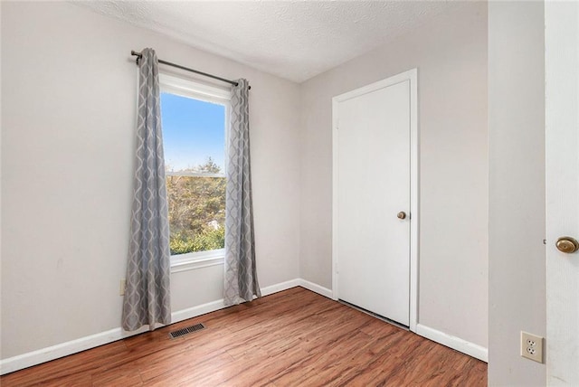 empty room with hardwood / wood-style flooring and a textured ceiling