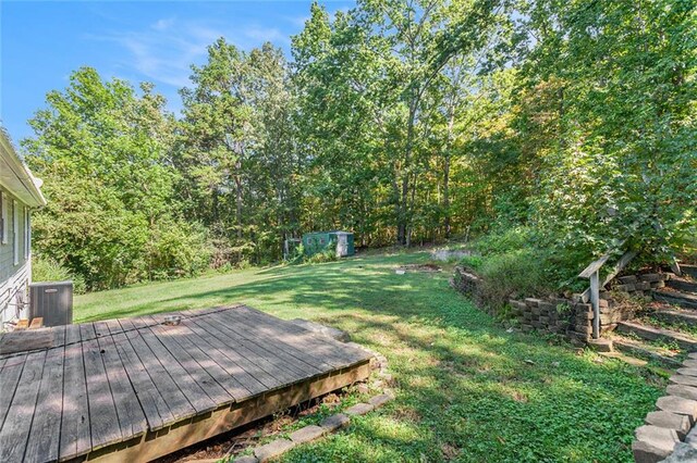 view of yard featuring a deck, central AC unit, and a storage unit