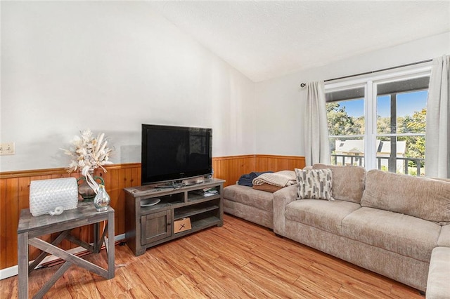 living room with lofted ceiling, wood walls, and light hardwood / wood-style flooring