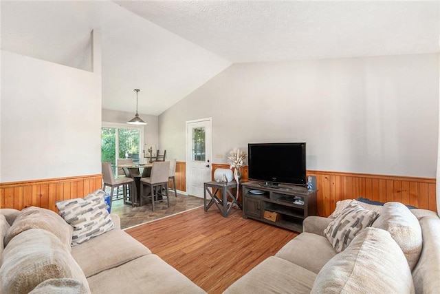 living room with hardwood / wood-style flooring, wooden walls, and high vaulted ceiling