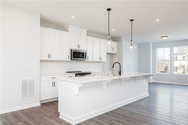 kitchen featuring sink, white cabinetry, stainless steel appliances, and an island with sink