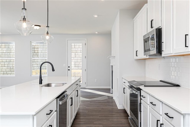 kitchen featuring pendant lighting, dark hardwood / wood-style floors, an island with sink, appliances with stainless steel finishes, and white cabinetry