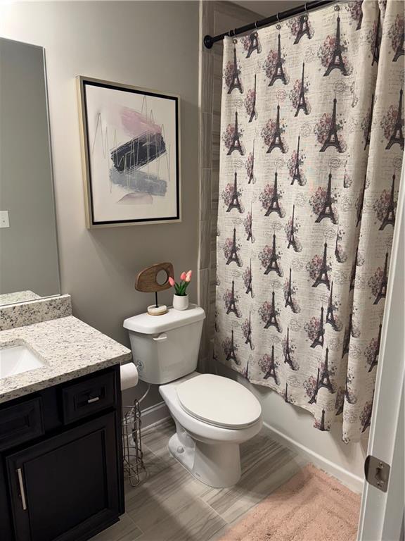 2709 Ratby Ln NE, Conyers, GA 30013 - bathroom featuring vanity, toilet, baseboards, shower / bath combo with shower curtain, and wood finished floors