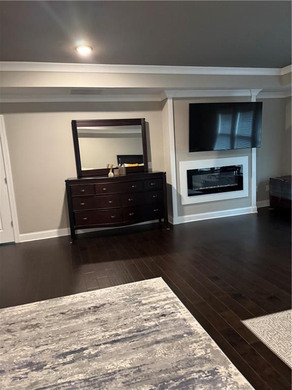 2709 Ratby Ln NE, Conyers, GA 30013 - bedroom with a glass covered fireplace, dark wood-type flooring, baseboards, and ornamental molding