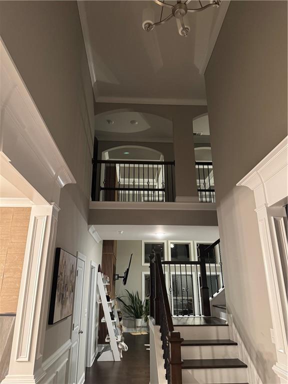 2709 Ratby Ln NE, Conyers, GA 30013 - stairway featuring a high ceiling, ornate columns, a chandelier, and ornamental molding
