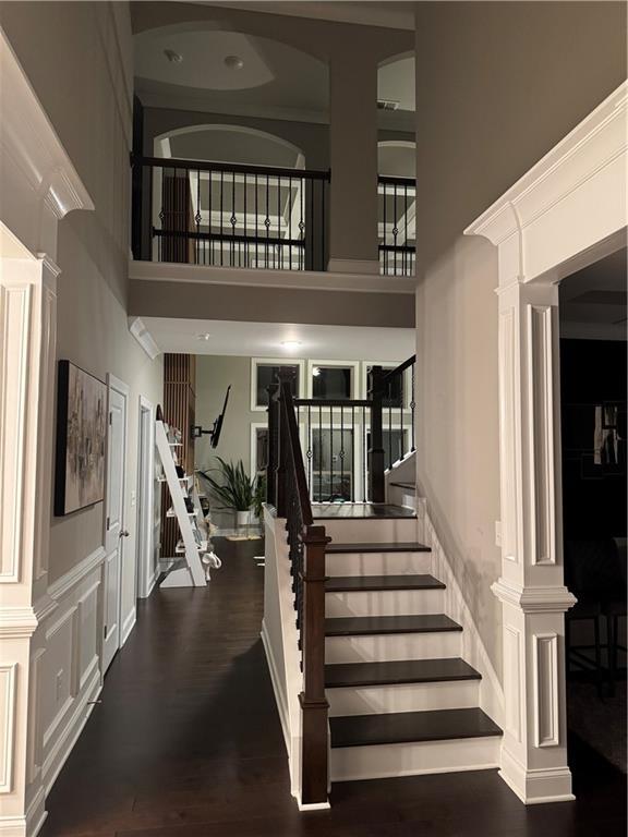 2709 Ratby Ln NE, Conyers, GA 30013 - stairway with a high ceiling, ornate columns, and wood finished floors