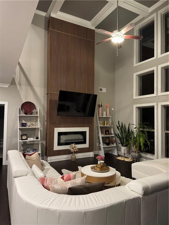 2709 Ratby Ln NE, Conyers, GA 30013 - living room featuring a ceiling fan, a fireplace, wood finished floors, coffered ceiling, and crown molding