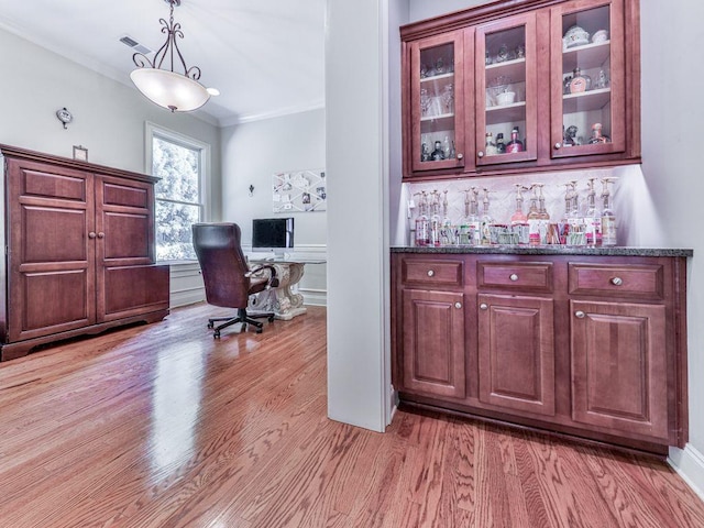 office with light wood-style floors, ornamental molding, and a bar