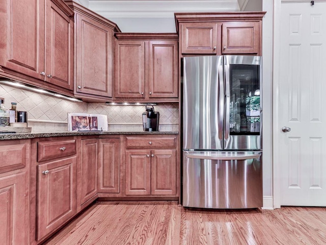 kitchen with smart refrigerator, backsplash, crown molding, dark stone countertops, and light wood-style flooring