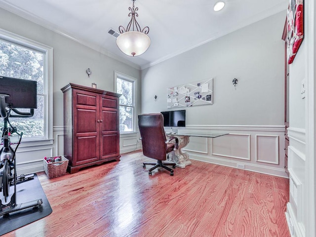 office featuring light wood finished floors, wainscoting, ornamental molding, and a decorative wall