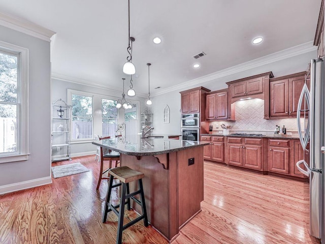 kitchen featuring stainless steel appliances, a sink, plenty of natural light, light wood-type flooring, and recessed lighting