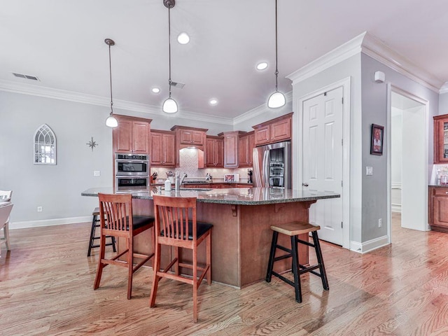 kitchen featuring stainless steel appliances, baseboards, a breakfast bar area, crown molding, and light wood-style floors