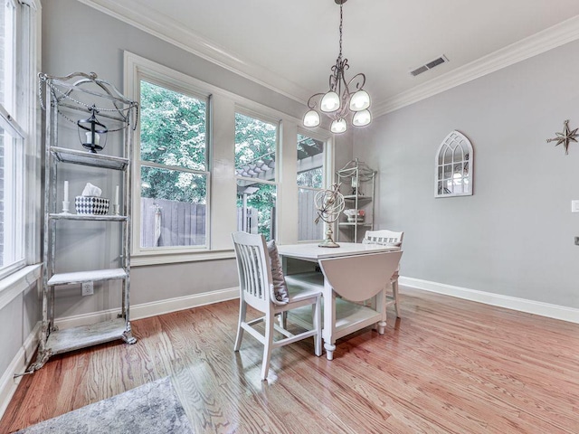 dining space with wood finished floors, ornamental molding, baseboards, and a chandelier