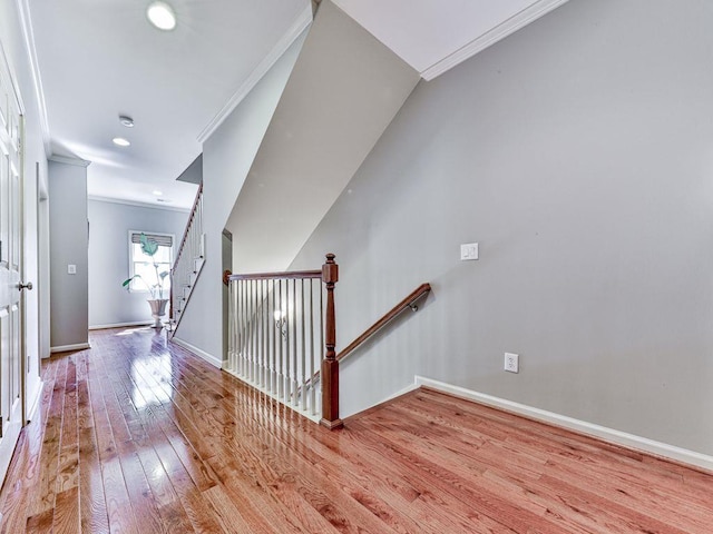 staircase with wood finished floors, ornamental molding, and baseboards