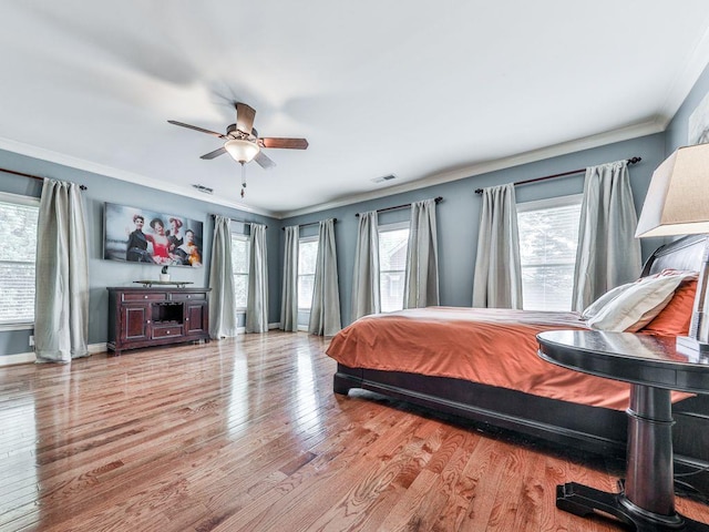 bedroom featuring wood finished floors, ornamental molding, a ceiling fan, and baseboards