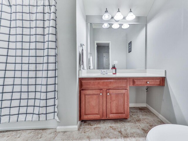 bathroom with vanity, a shower, tile patterned floors, and baseboards