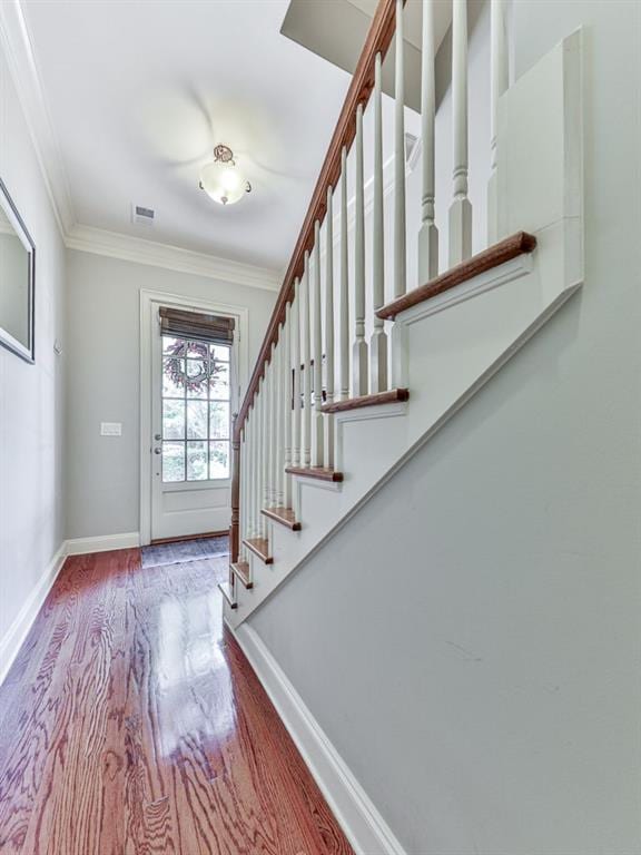 entryway featuring wood finished floors, stairs, ornamental molding, and baseboards