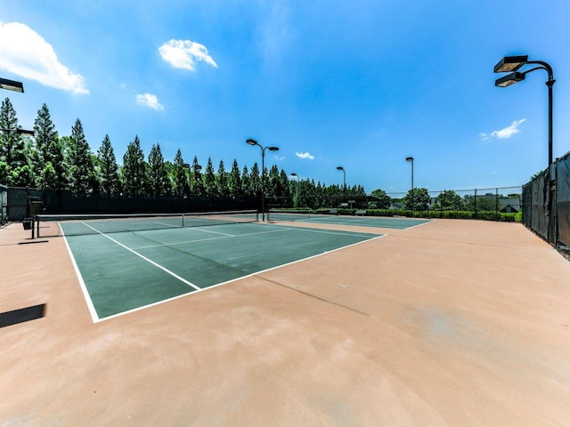 view of tennis court featuring fence and community basketball court