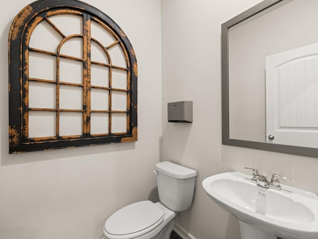 bathroom with a sink, baseboards, and toilet